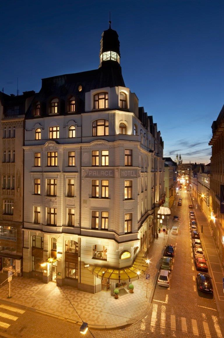 Art Nouveau Palace Hotel Praha Bagian luar foto The photo shows a beautifully illuminated hotel building at dusk. The architecture has a classic style, featuring several large windows with warm lighting that gives a welcoming appearance. The hotel bears the name "Palace Hotel" prominently displaye