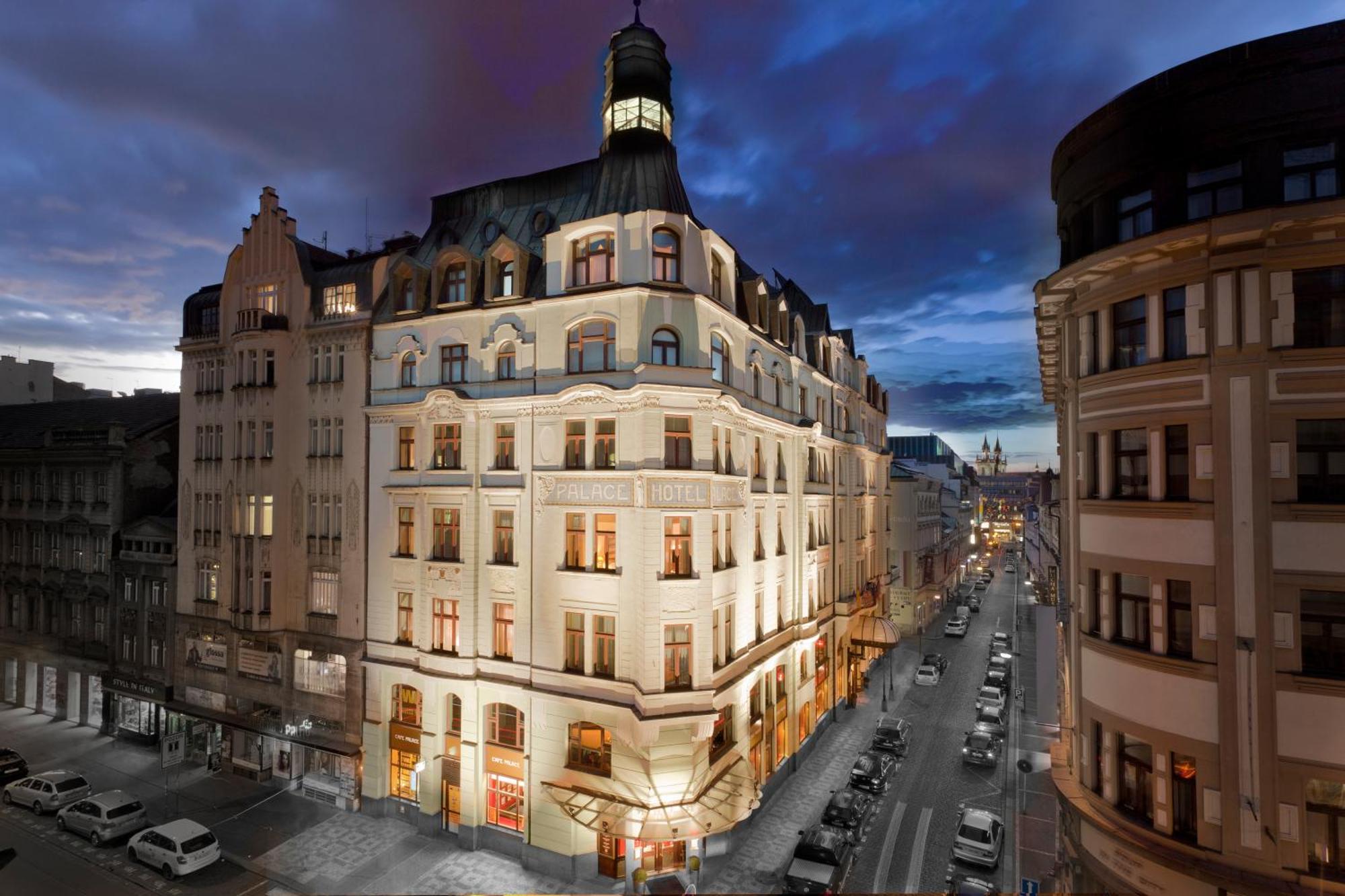 Art Nouveau Palace Hotel Praha Bagian luar foto The image shows a beautifully designed building at dusk. The structure features an elegant architectural style, with distinct elements like a tower or cupola at the top. The facade is illuminated, highlighting the intricate details of the design. The