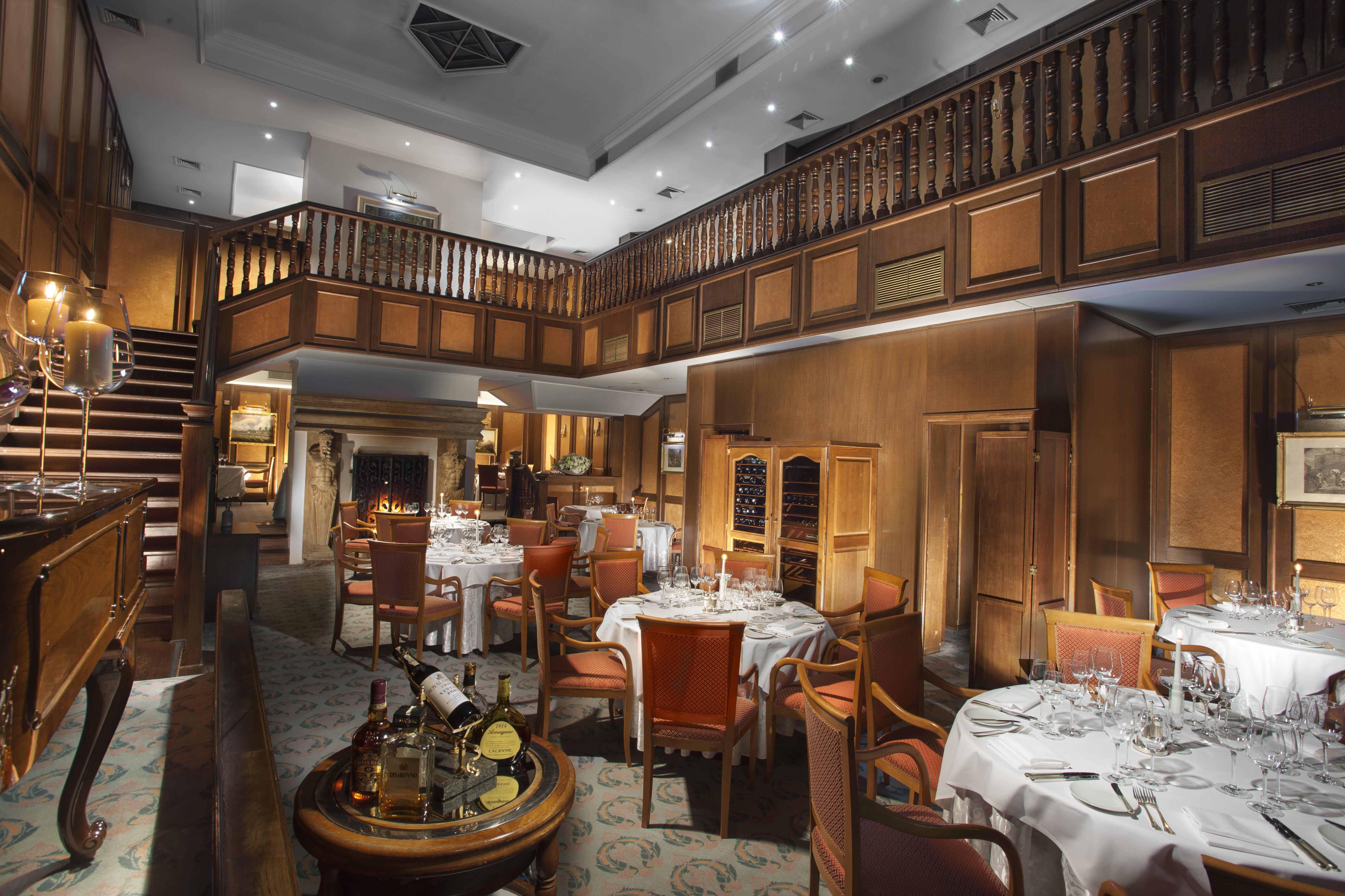 Art Nouveau Palace Hotel Praha Bagian luar foto The photo shows an elegant restaurant interior. It features a spacious dining area with multiple round tables, each set with white tablecloths and fine dining essentials such as glassware and cutlery. The decor includes rich wooden paneling on the wa